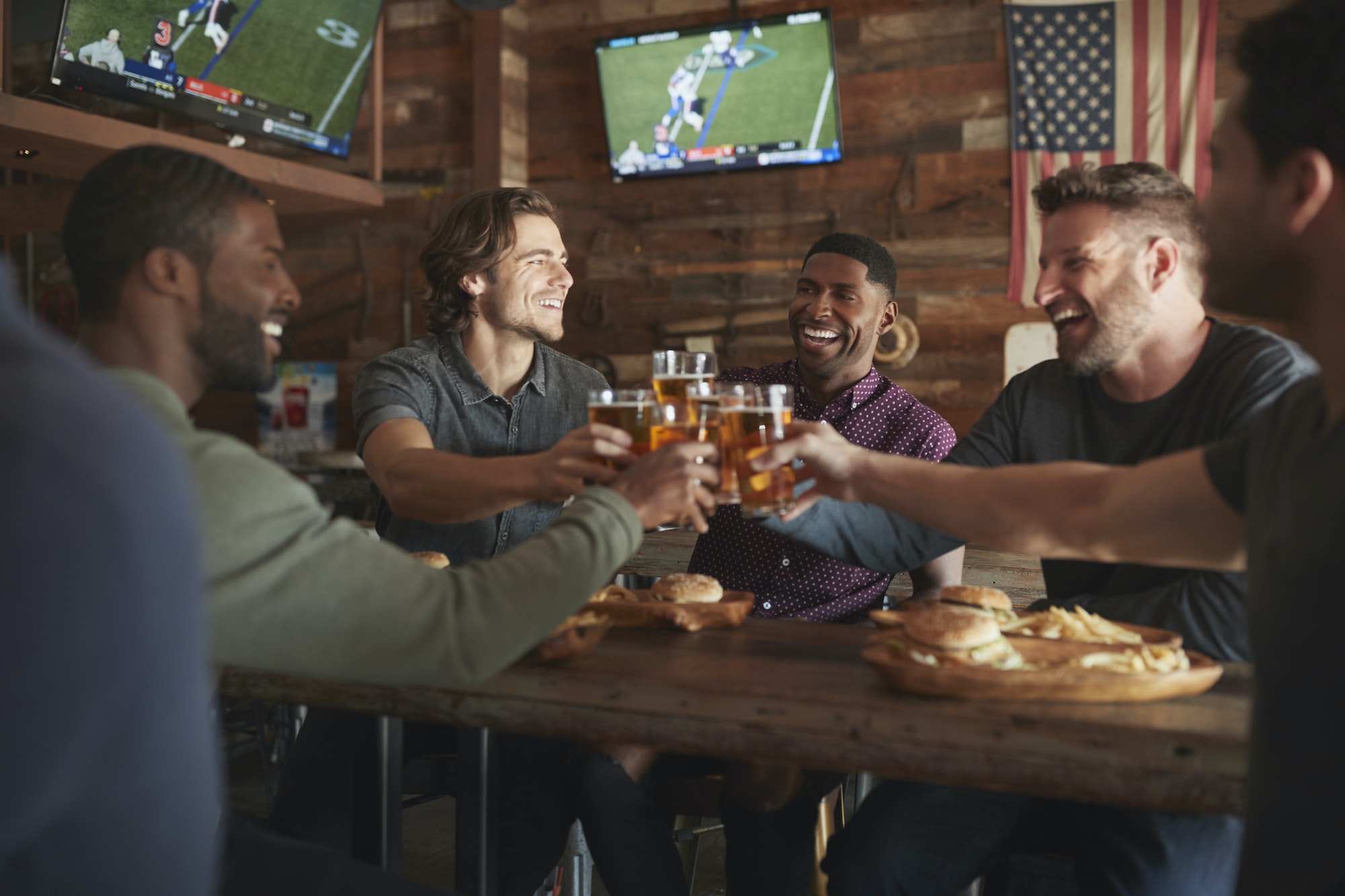 Amis buvant de la bière et mangeant des hamburgers au bar des sports