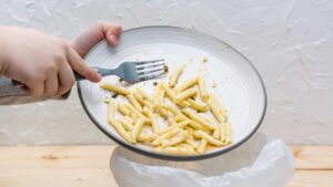 Enfant qui jette ses pâtes à la poubelle