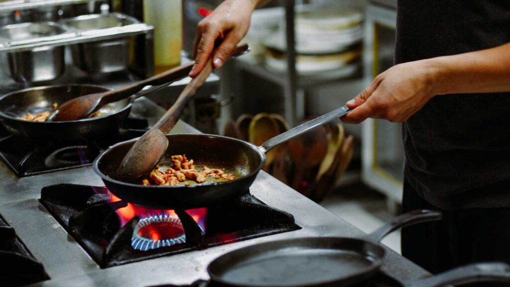 Cuisinier qui est entrain de cuisiner à la poêle 